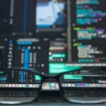 Ecrã de computador com linhas de código e óculos em primeiro plano