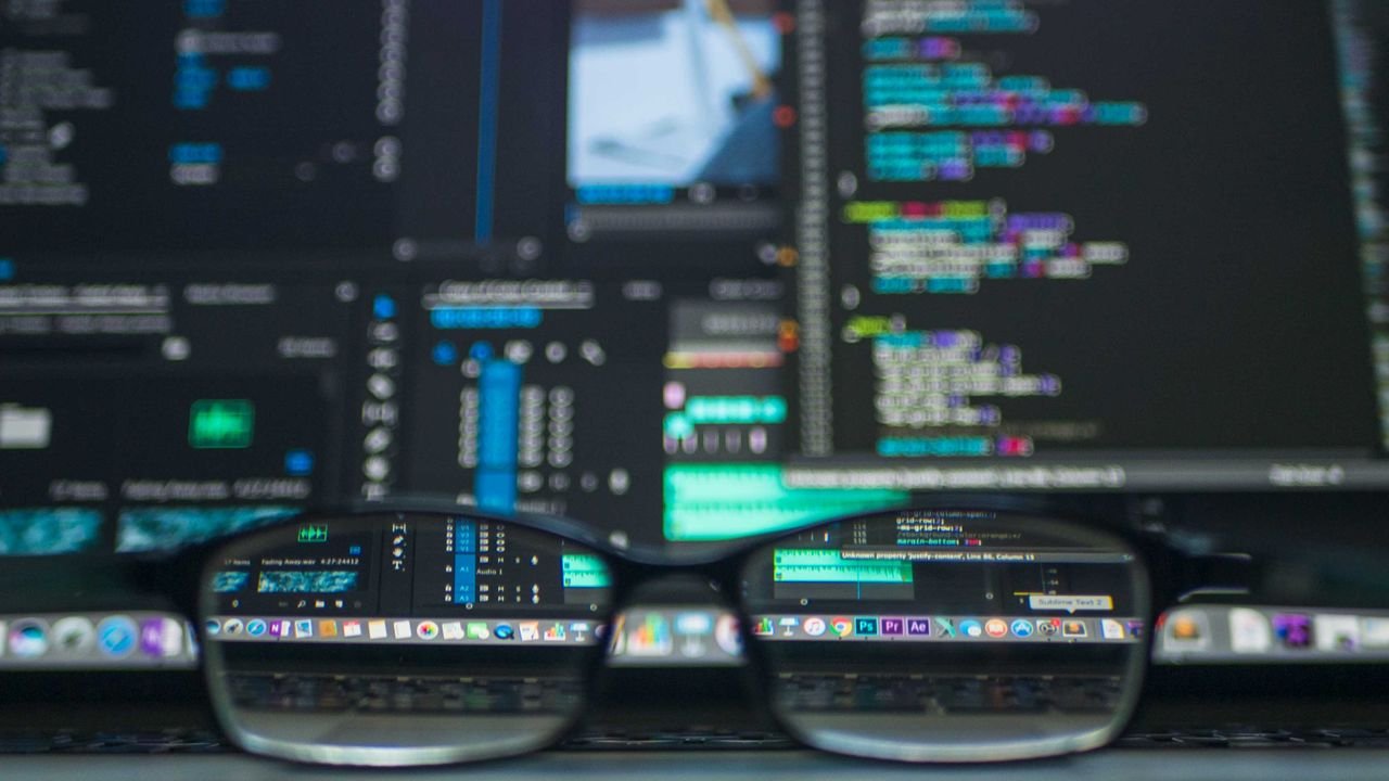 Ecrã de computador com linhas de código e óculos em primeiro plano