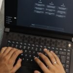 Mãos a escrever num portátil com uma interface de chatbot de IA no ecrã